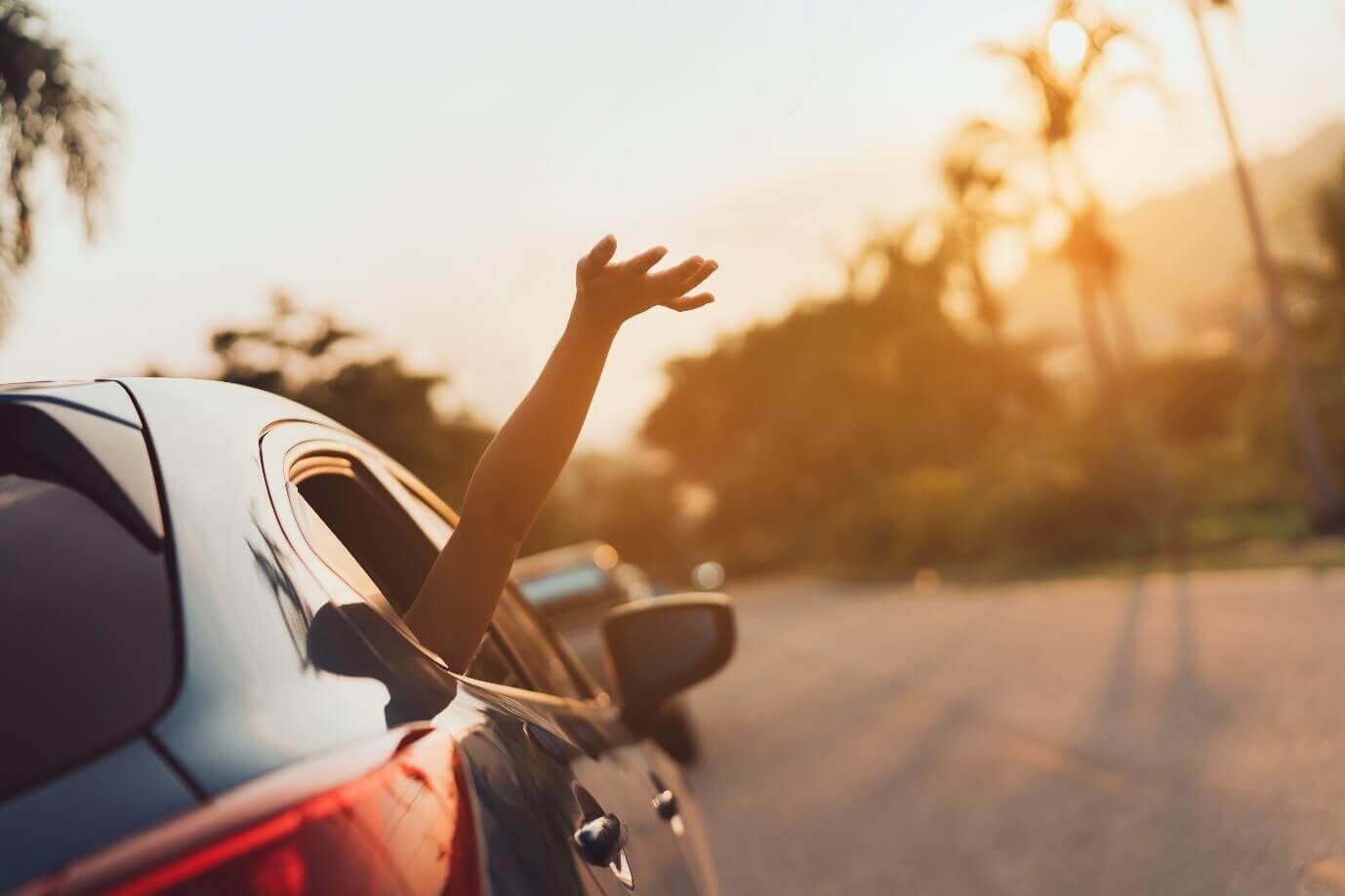 A person with their arm out of the back car window